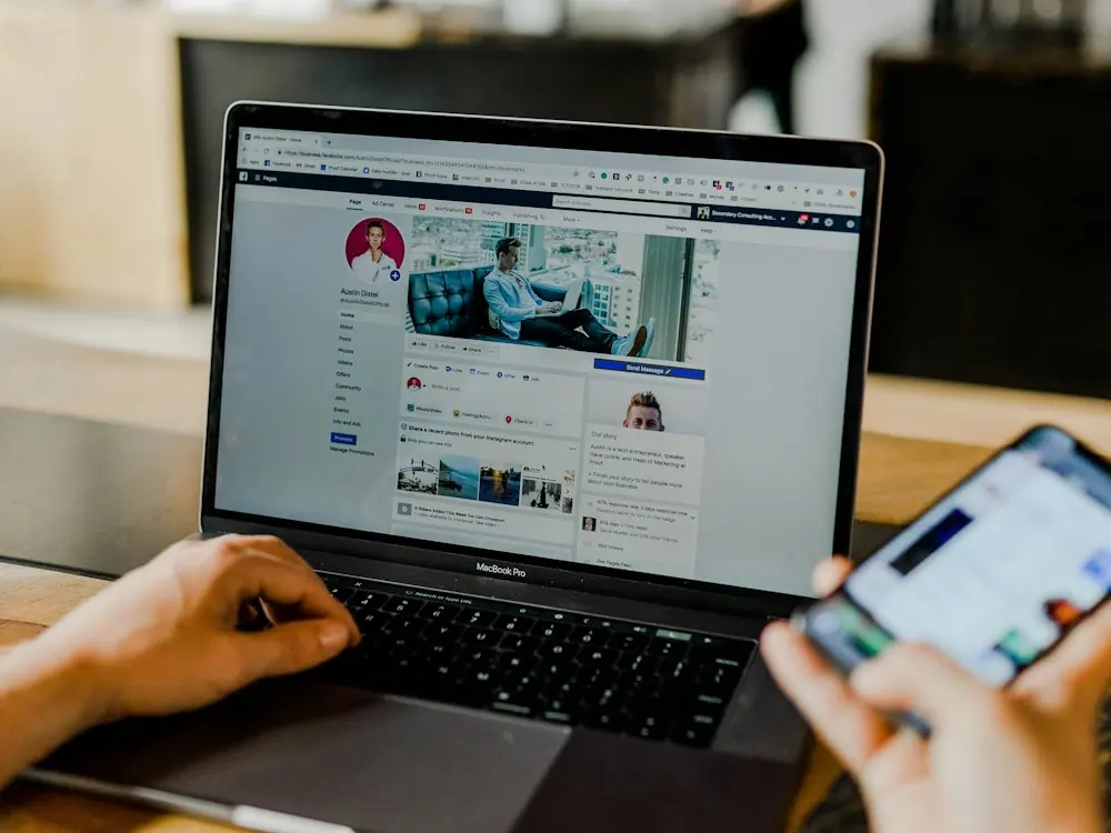 A person using a laptop and a phone with social media open