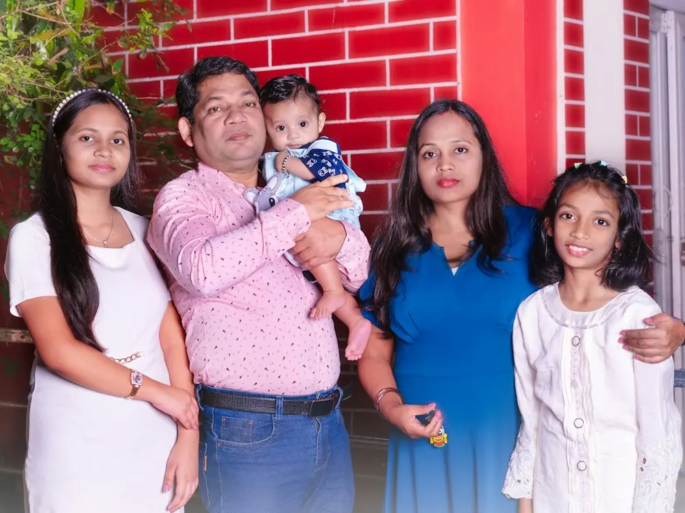 A smiling Indian family of five standing together